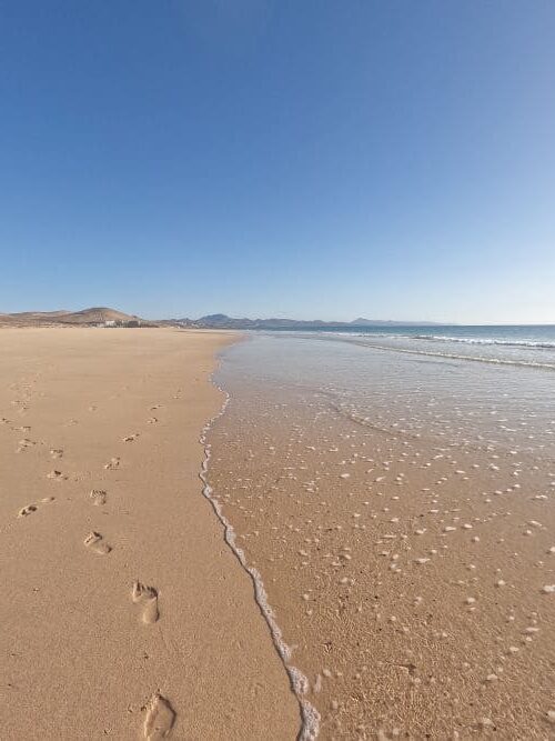 langer Sandstrand mit Fußspuren im Sand